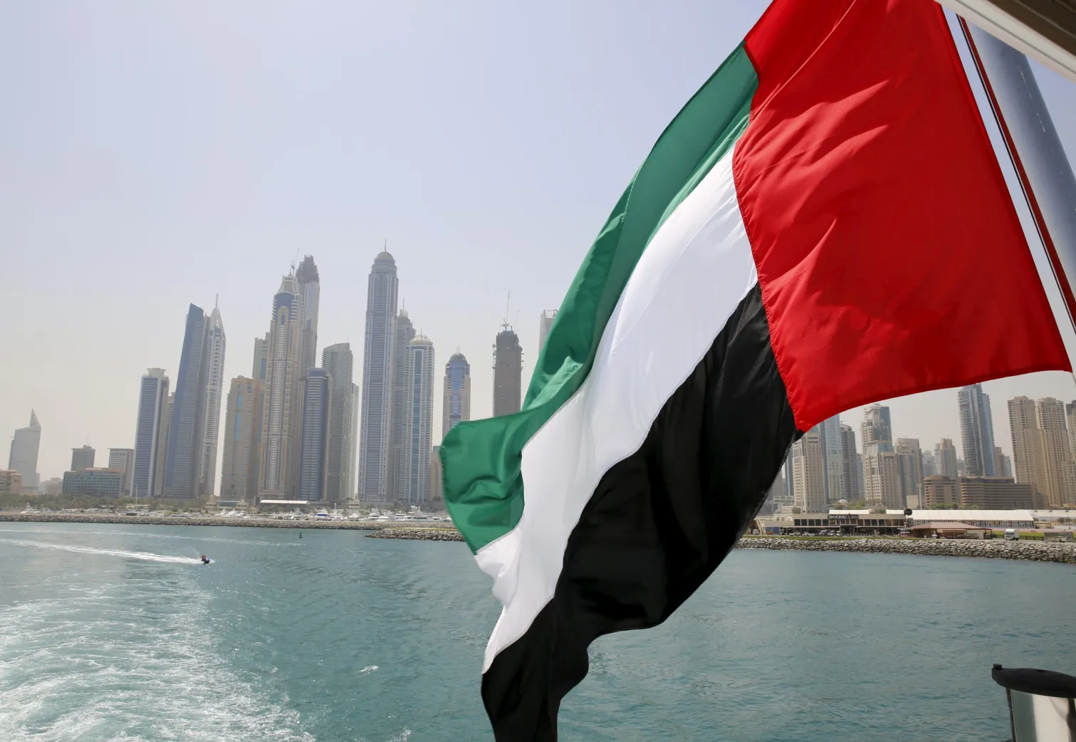 The uae flag flies over the dubai marina, with the skyline visible.