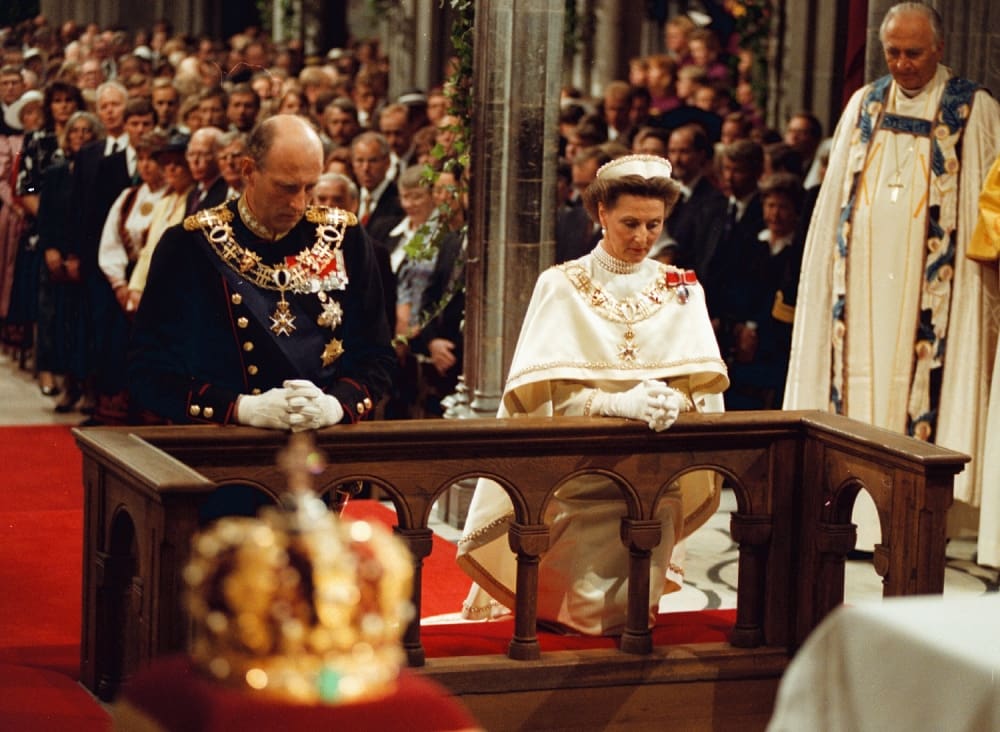 Hm king harald v and hm queen sonja by the altar with their crowns on the pidestals.